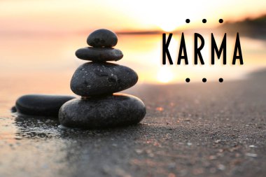 Karma kavramı. Gün batımında deniz kenarında kumdaki taşlar
