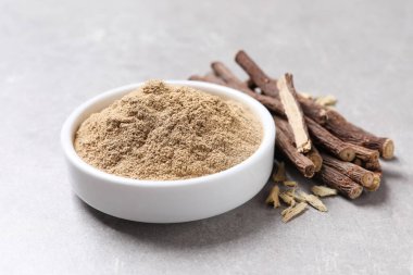 Gri masada kurutulmuş meyan kökü ve toz, yakın plan.
