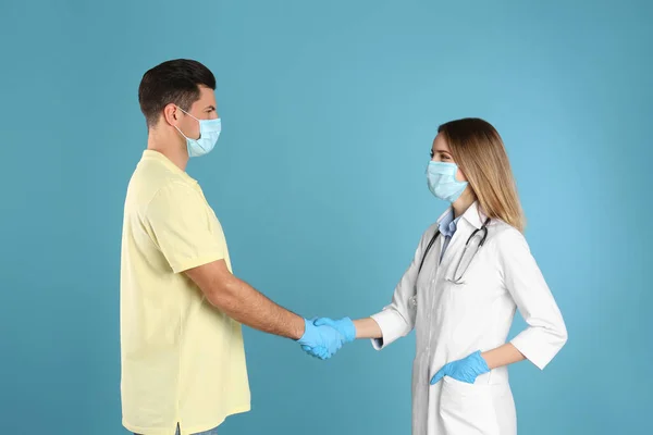 Medico Paziente Maschere Protettive Stringendo Mani Sfondo Azzurro — Foto Stock