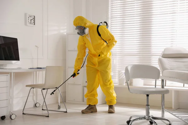 防護服の男が医者のオフィスを消毒してる 医学的消毒 — ストック写真