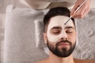 Spa salonunda adamın yüzüne maske takan bir kozmetikçi. Metin için boşluk