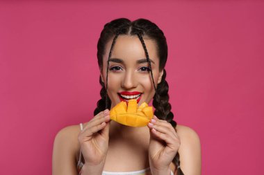 Pembe arka planda taze mangolu genç bir kadın. Egzotik meyve