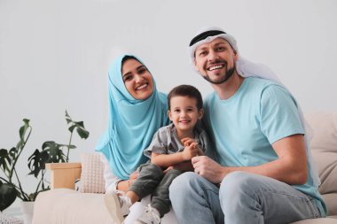 Oturma odasındaki kanepede mutlu Müslüman aile.