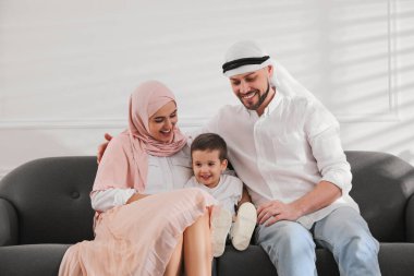 Mutlu Müslüman aile evdeki kanepede birlikte vakit geçiriyor.