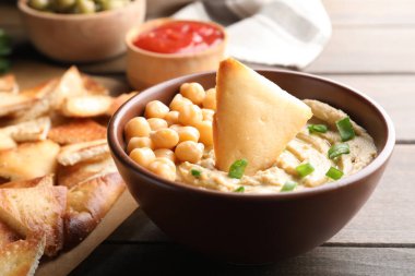 Tahta masada humus ve nefis pita cipsleri, yakın plan.