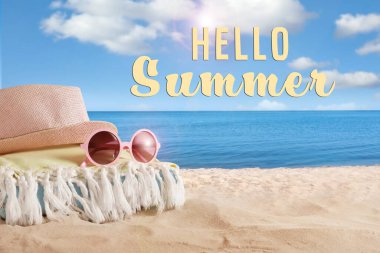 Merhaba Summer. Denize yakın kumda şapka, havlu ve güneş gözlüğü