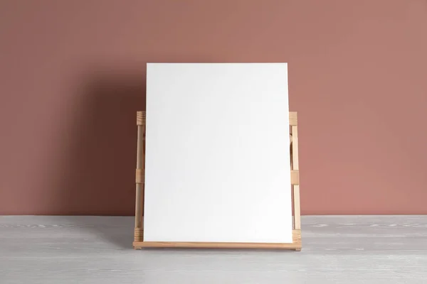 Wooden easel with blank canvas on white table