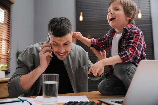 Overwhelmed man combining parenting and work at home