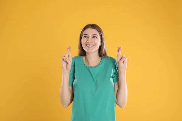 Mulher Com Dedos Cruzados Fundo Amarelo Conceito Superstição — Fotografia de Stock