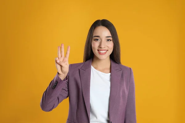 Mujer Chaqueta Violeta Mostrando Número Tres Con Mano Sobre Fondo — Foto de Stock