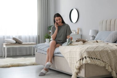 İş günü için kıyafet seçerken telefonda konuşan genç bir kadın. Sabah rutini