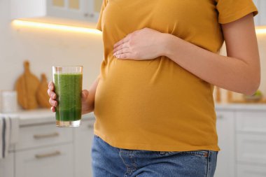 Mutfakta smoothie ile genç hamile kadın, yakın plan. Sağlıklı beslenme
