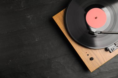 Siyah arka planda vinil plağı olan turntable, üst görünümde. Metin için boşluk