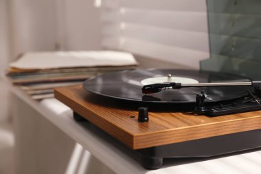 Odadaki pencere pervazında vinil disk olan şık bir pikap.