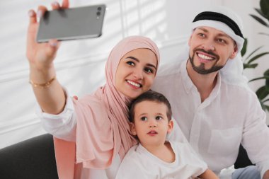 Mutlu Müslüman aile evde selfie çekiyor.
