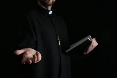İncil 'i olan rahip karanlık arka planda dua ediyor, yakın plan