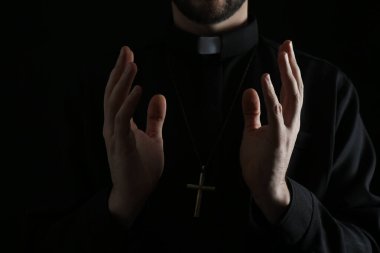Cüppeli rahip karanlık arka planda dua ediyor, yakın plan