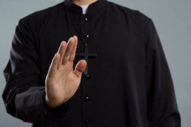 Rahip gri arka planda kutsama hareketi yapıyor, yakın plan.