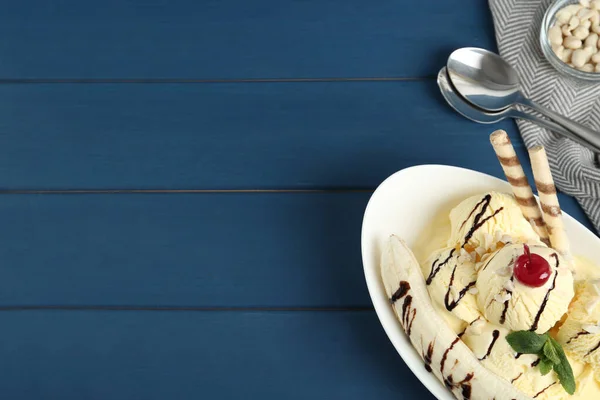 Delicious dessert with banana ice cream on blue wooden table, flat lay. Space for text