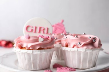 Pembe kremalı lezzetli kekler ve tabakta bebek partisi için kaplar, yakın plan.