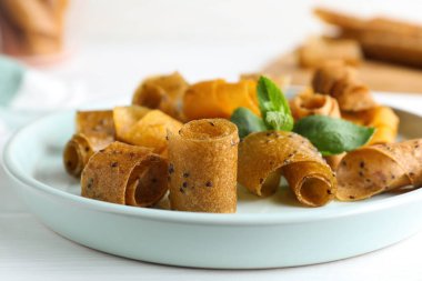 Lezzetli meyve derisi beyaz ahşap masada yuvarlanıyor, yakın plan.