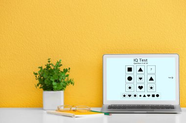 Sarı duvarın yanında IQ testi olan modern bir bilgisayar.