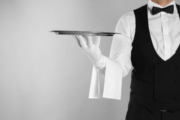 Butler with tray on light grey background, closeup. Space for text