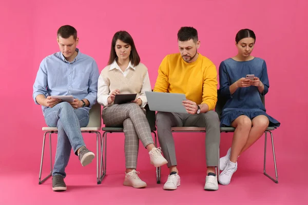 People waiting for job interview on pink background