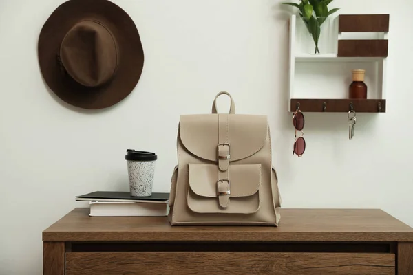 Stylish urban backpack on wooden chest of drawers in hallway