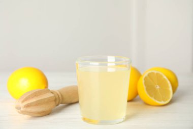 Taze sıkılmış meyve suyu, beyaz ahşap masada limon ve süt tozu.