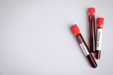 Açık gri arkaplan üzerinde kan örnekleri olan test tüpleri, düz zemin ve metin için alan. Doping kontrolü