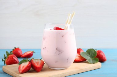 Açık mavi ahşap masada çilekli nefis bir içecek.