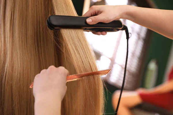 发型师在沙龙 特写镜头用扁铁直女人的头发 — 图库照片