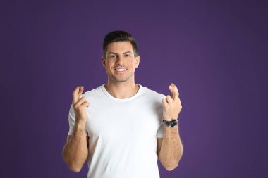 Mor arka planda çapraz parmaklı bir adam. Batıl inanç kavramı