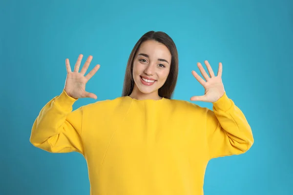 Kobieta Pokazuje Numer Dziesięć Rękami Jasnoniebieskim Tle — Zdjęcie stockowe