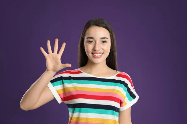 Женщина Показывает Номер Пять Рукой Фиолетовом Фоне — стоковое фото