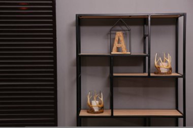 Gri duvarın yanında dekorasyonu olan şık bir raf ünitesi. İç tasarım