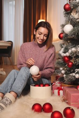 Evde Noel ağacı süsleyen genç bir kadın.