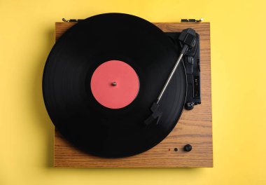 Sarı arka planda diski olan modern vinil plak çalar, üst görünüm