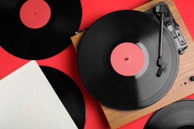 Kırmızı arkaplanda modern oyuncu ve vinil kayıtları, düz konum