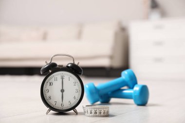 Alarm saati, mezura ve ahşap zemindeki dambıllar. Sabah egzersizi