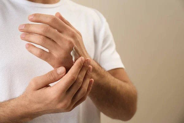 Mężczyzna Nakładający Krem Dłoń Beżowe Tło Zbliżenie — Zdjęcie stockowe