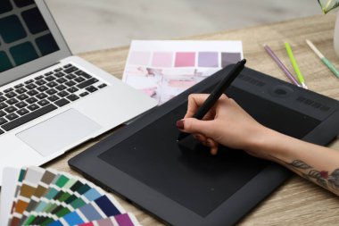 Ahşap masada grafik tableti olan profesyonel tasarımcı, yakın plan.