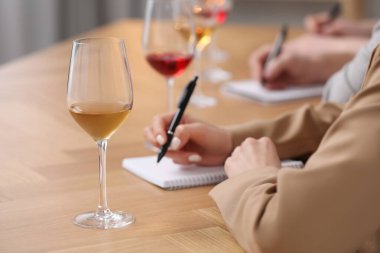 Şarap tadımı sırasında şarap garsonları not alıyor. Kapalı bir masa, yakın çekim.