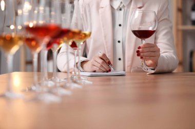 Sommelier içerideki masada farklı türde şarap tadıyor, yakın plan.