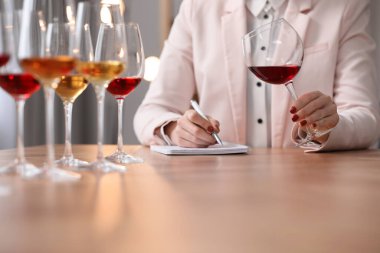 Sommelier içerideki masada farklı türde şarap tadıyor, yakın plan.