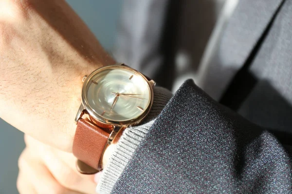 Man with luxury wrist watch on blurred background, closeup