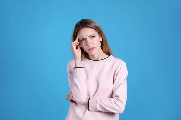 Portrait of stressed young woman on light blue background