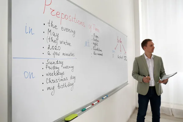英語教師が教室でホワイトボード近くの時間の前置詞について授業を行う — ストック写真