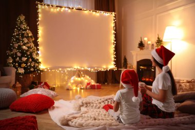 Anne ve kızı evde video projektörüyle film izliyorlar. Sıcak Noel atmosferi